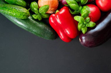 Karanlık arka planda taze sebzeler. Biber, kabak, patlıcan, soğan, domates, fesleğen.