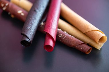 Masanın üzerinde renkli meyve ruloları var. Meyvelerin doğal tatlısı. Meyve pastil çarşafları.