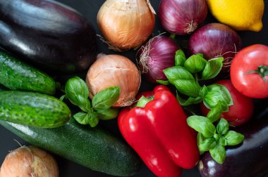 Çeşitli taze sebzelerin yatay arka planı. Patlıcan, sarı soğan, kırmızı soğan, salatalık, domates, limon, kabak, fesleğen.