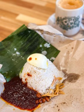 Klasik Malezya Nasi Lemak muz yaprağı ve balmumu kağıdında sunuluyor, içinde hindistan cevizi pilavı, sambal, haşlanmış yumurta, kızarmış ançüez ve kavrulmuş fıstık bulunuyor..