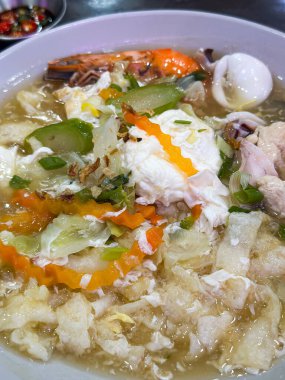 Karides, mürekkep balığı, sebze ve sarımsak ve soğanla süslenmiş, gevrek erişteli bir kase deniz ürünleri çorbası..