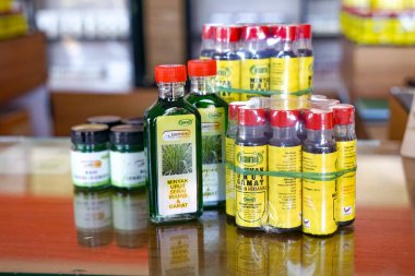 Langkawi, Kedah, Malezya, 3 Aralık 2025: Bir mağaza tezgahında geleneksel ilaç ve doğal sağlık ürünleri sergilenen limon otu ve gamat ile şişelenmiş bitkisel masaj yağları.