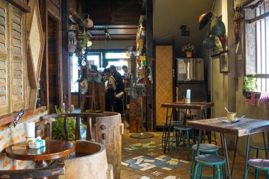 Kedah, Malezya, 5 Aralık 2025: Ahşap masalar, metal tabureler, yumuşak gün ışığı, dokulu duvarlar ve gevşetilmiş bir vintage atmosferi olan sıcak bir köy kafesi..