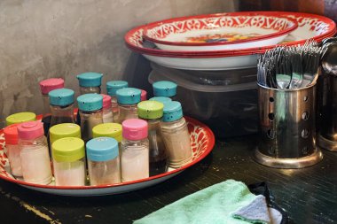 Konforlu bir yemek veya restoran ortamında canlı sos kavanozları, diş mineleri ve çatal bıçak takımlarıyla organize edilmiş mutfak..