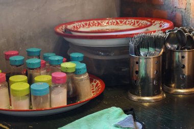 Konforlu bir yemek veya restoran ortamında canlı sos kavanozları, diş mineleri ve çatal bıçak takımlarıyla organize edilmiş mutfak..