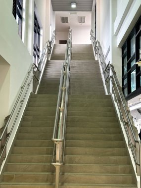 Modern bir iç mekan ortamında metal tırabzan ve temiz mimari simetriye sahip geniş merdiven..