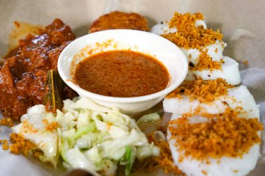 Balmumu kağıtta servis edilen pirinç kekleri, rendang, sebze ve fıstık soslu renkli Longong kertenkele tabağı..