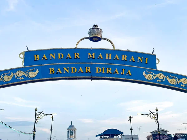 Johor, Malezya, 10 Ocak 2026: Taçlı ve altın harfli dekoratif kemer açık mavi gökyüzü altında 