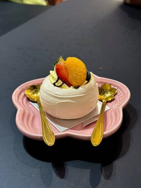 Krema, böğürtlen ve narenciye ile kaplanmış zarif pavlova tatlısı, pembe çiçek şeklinde bir tabakta servis edilir..