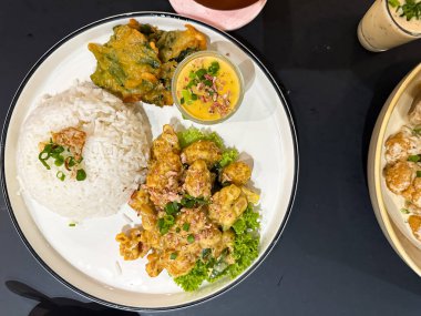 Pirinç soslu Asya usulü renkli yemek, soslu protein, tempura yeşili ve beyaz tabakta sos..