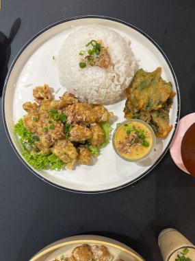 Pirinç soslu Asya usulü renkli yemek, soslu protein, tempura yeşili ve beyaz tabakta sos..