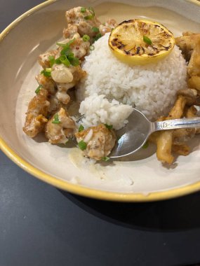 Limon, kremalı tavuk, mantar ve yeşil soğanla süslenmiş bir tabak pirinç..