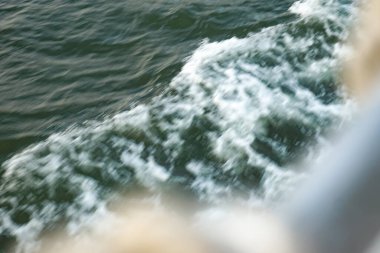 Köpüklü tekne hareket halinde koyu yeşil su yüzeyinde ilerliyor..