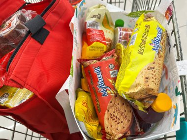 Johor, Malezya, 10 Şubat 2026: Market arabasında çeşitli bakkaliye ve paketlenmiş gıda eşyalarıyla dolu alışveriş poşetleri.