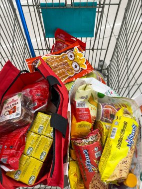 Johor, Malezya, 10 Şubat 2026: Market arabasında çeşitli bakkaliye ve paketlenmiş gıda eşyalarıyla dolu alışveriş poşetleri.