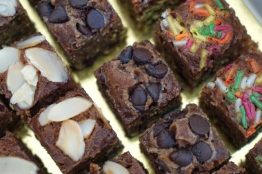 Badem, cips ve serpiştirilmiş nemli çikolatalı kek kareleri seçici bir odak noktası. Kapat..