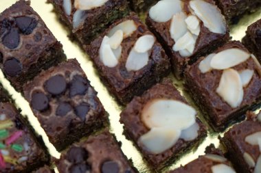 Badem, cips ve serpiştirilmiş nemli çikolatalı kek kareleri seçici bir odak noktası. Kapat..