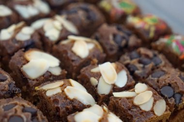 Badem, cips ve serpiştirilmiş nemli çikolatalı kek kareleri seçici bir odak noktası. Kapat..