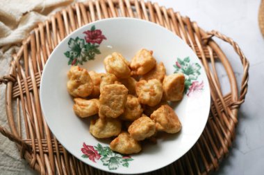 Çiçekli seramik tabakta servis edilen gevrek altın rengi çörekler örülmüş rattan tepsisine konur, hafif yüzeyde geleneksel ev yapımı aperatif sunumu yapılır..