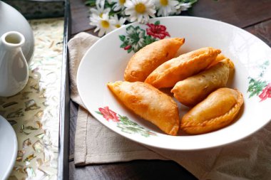 Köy çayı setiyle bir tabak altın körili puf ve ahşap arka planda papatyalar..