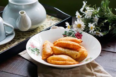 Köy çayı setiyle bir tabak altın körili puf ve ahşap arka planda papatyalar..