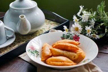 Koyu ahşap arka planda çiçek tabağına yerleştirilmiş altı altın körili puf..