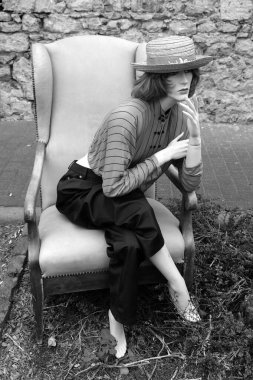 Altmışlı yılların nostaljik görüntüsüyle bir koltukta oturan manken ve 70 'li yılların klasik araba etkinliği olan Wettenberg' deki Altın Eskiler Krofdorf-Gleiberg 'de Hesse, Almanya' daki Giessen yakınlarında.