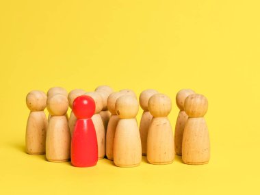 Sarı arka planda bir grubun önünde duran kırmızı ahşap figür..