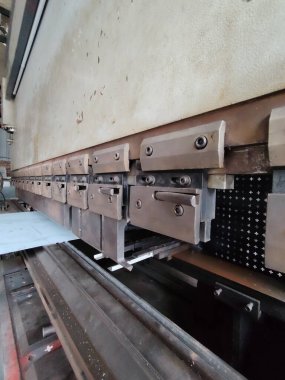 Sheet metal being bent by a press brake machine.