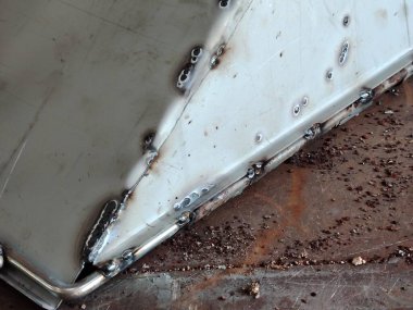 Bir atölyedeki açık renkli metal levha üzerindeki taze kaynak ve dikişleri kapatın..