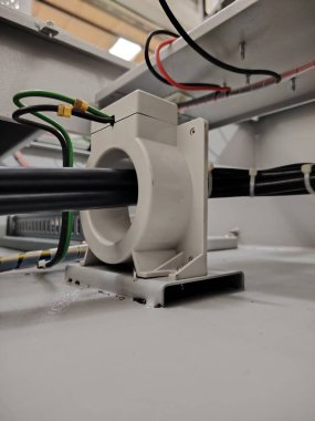 Sistem izleme için ana güç kablosunu çevreleyen beyaz akım sensörü.