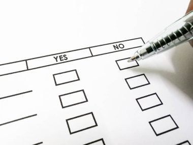 Önemli bir belgede eleştirel bir evet ya da hayır seçimi yapmaya hazırlanan, kalemle yakın plan bir el..