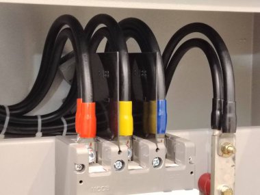 Organize siyah güç kabloları ve üç aşamalı güç kaynağı için izole terminallerin yer aldığı endüstriyel elektrik kurulumu.