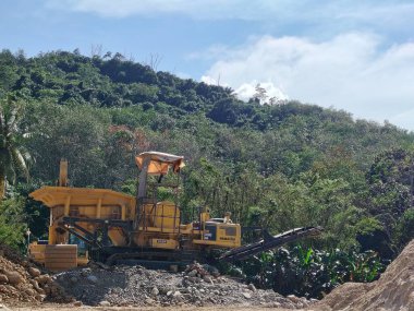 İş Başındaki Endüstriyel Makineler: Tropikal Bitkilerle çevrili Büyük Kaya Ezici Tesis.