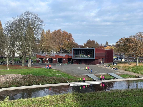 Bir sonbahar günü Den Bosch 'taki bir kanalda insanların su sporları tesislerinin yakınındaki açık hava aktivitelerinin keyfini çıkardıkları kürek kulübü binası ve rıhtımı..