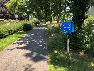 13 sarı yıldızlı mavi yol işareti bisiklet yolu üzerinde sınır çizgisi olan Belçika sınırını gösteriyor..