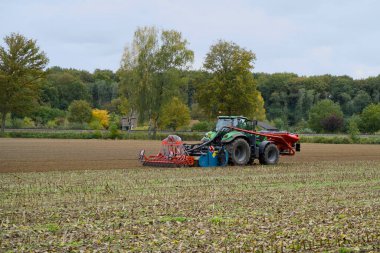 Önünde tohum, arkasında tohum ekme kutusu olan traktör..