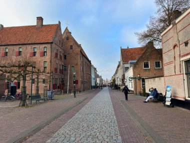 Ortaçağ Hanedan kenti Elburg 'da duvarları olan tarihi bir sokak, Hollanda' nın Vischpoort kentinin kapısına doğru uzanan eski tuğla manastır ve kaldırımlı sokak. Elburg, Hollanda, Aralık 05, 2025
