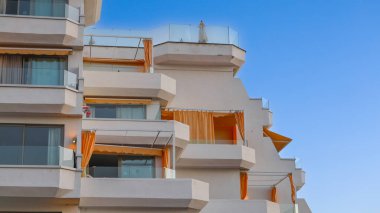Luxury hotel resort with modern white terraces and orange awnings under a clear blue sky, capturing the upscale coastal tourism atmosphere of the Canary Islands