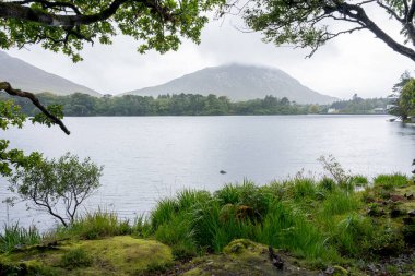 Kylemore Manastırı Gölü: İrlanda 'da bir tepenin eteğindeki gölle çevrili beyaz bir kale / monestery..