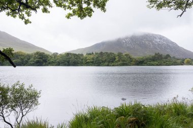 Kylemore Manastırı Gölü: İrlanda 'da bir tepenin eteğindeki gölle çevrili beyaz bir kale / monestery..