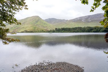 Kylemore Manastırı Gölü: İrlanda 'da bir tepenin eteğindeki gölle çevrili beyaz bir kale / monestery..