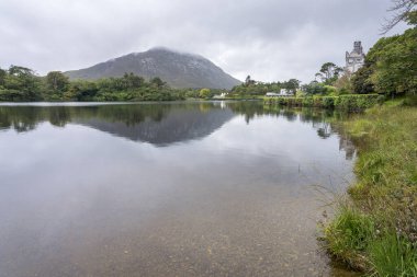 Kylemore Manastırı Gölü: İrlanda 'da bir tepenin eteğindeki gölle çevrili beyaz bir kale / monestery..