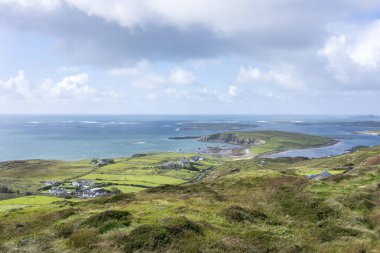 Arka planda Atlantik Okyanusu ve bulutlu mavi gökyüzü ile inşa ve çayır manzarası.
