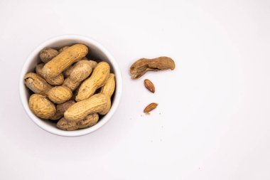 Maymun fındıkları beyaz bir tabakta sade bir arka planda, yemek, atıştırmalık ve malzeme temaları için uygun bir şekilde düzenlenmiştir..