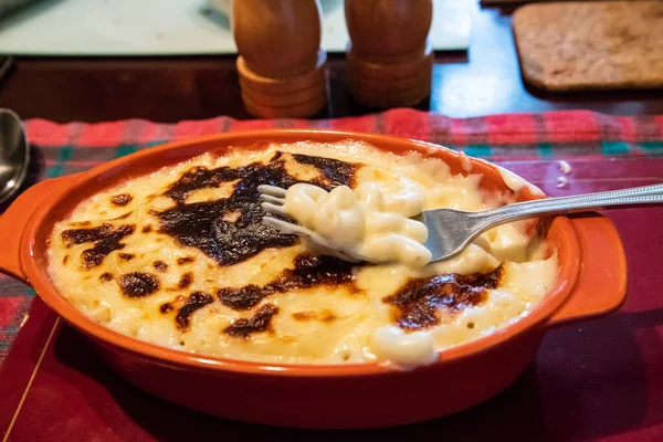 Turuncu seramik bir tabakta kremalı makarna peyniri, üzerinde makarna olan altın fırında pişmiş çatal, konforlu yiyecek konsepti..