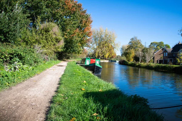 Enfield Lock 'taki Lea Nehri' nin güneşli manzarası, Enfield, Kuzey Londra 'da bir kanal teknesi ve nehir kenarındaki evleri gösteriyor..