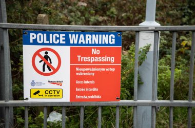 Demiryolu platformunda güvenlik, güvenlik ve demiryolu ağına kısıtlı erişimin yasak olduğunu belirten bir polis uyarı levhası..