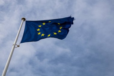 Rüzgarda dalgalanan Avrupa Birliği bayrağı, parlak doğal gökyüzüne karşı mavi, Avrupa 'yı, birliği ve kimliği simgeleyen,