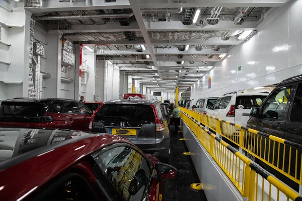 Portsmouth 'tan Caen' e giden bir feribotta araç güvertesi Avrupa 'nın deniz yolculuğu ve taşımacılığı sahnesi olan endüstriyel iç kısımda park halindeki araçları gösteriyor..